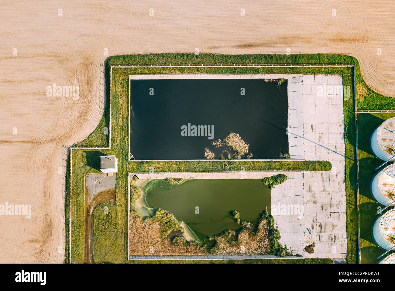 Aerial View Of Retention Basins, Wet Pond, Wet Detention Basin Or Stormwater Management Pond Near Biogas Bio-gas Plant From Pig Farm. Artificial Pond With Vegetation Around Perimeter. Stock Photo