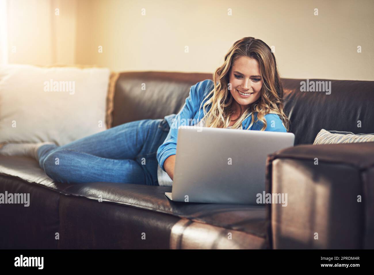 Make more time for yourself. a relaxed young woman using a laptop on the sofa at home. Stock Photo