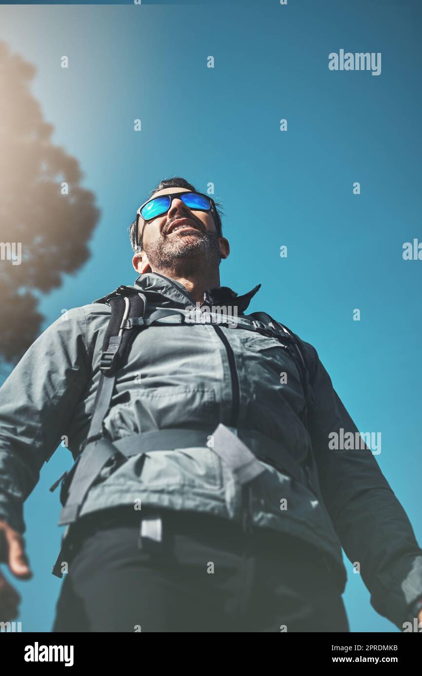 Sky high with belief. Low angle shot of a middle aged man hiking in the mountains. Stock Photo