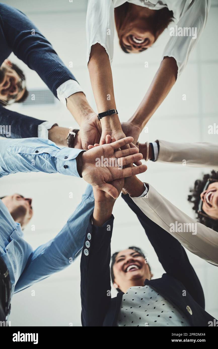 Hands stacked and piled showing team unity, strength or motivation among creative business colleagues from below. Excited, laughing and huddled group of inspired business people ready for success Stock Photo