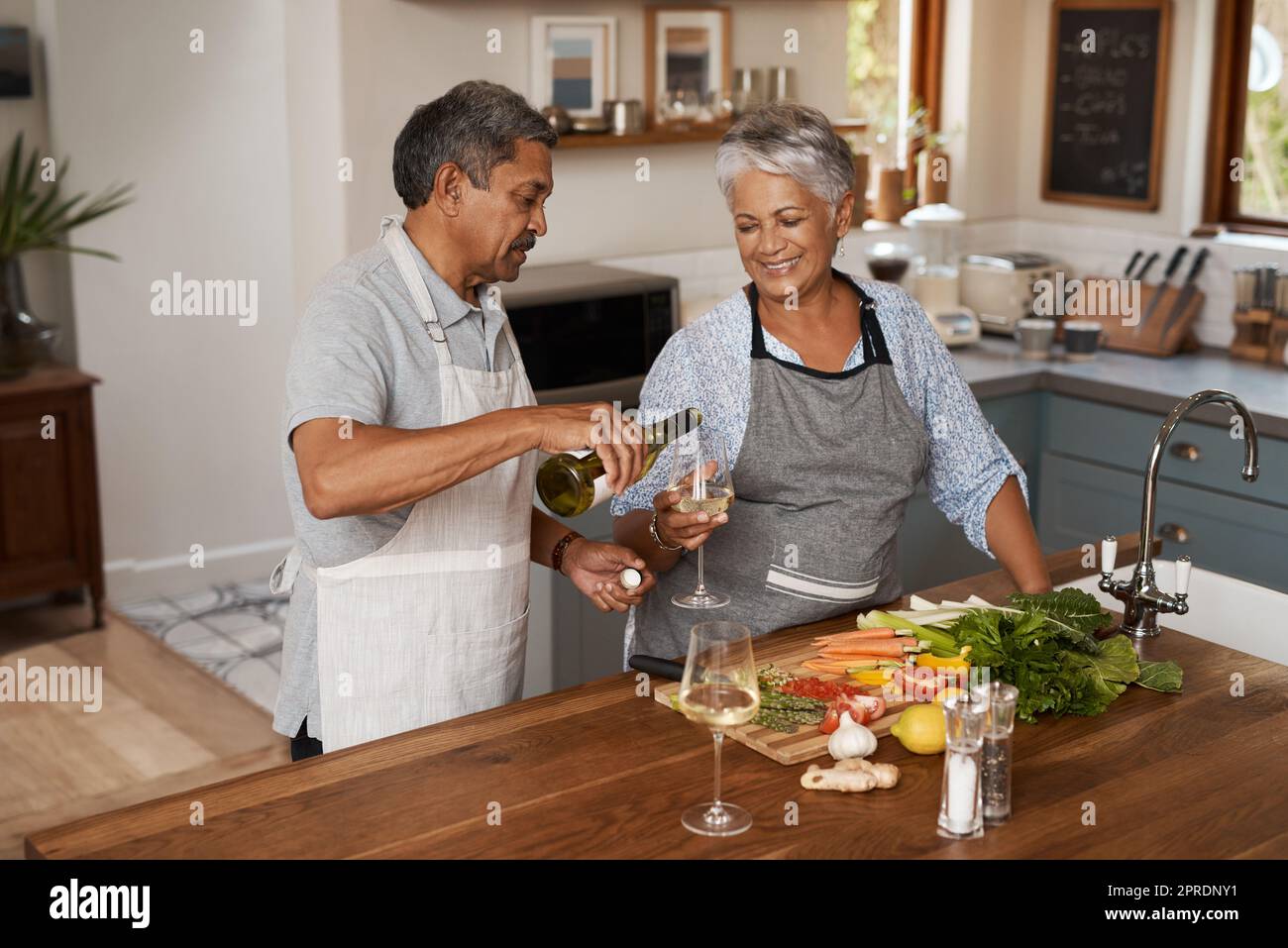 Retirement - no work, no worries. a happy mature couple drinking wine while cooking a meal together at home. Stock Photo
