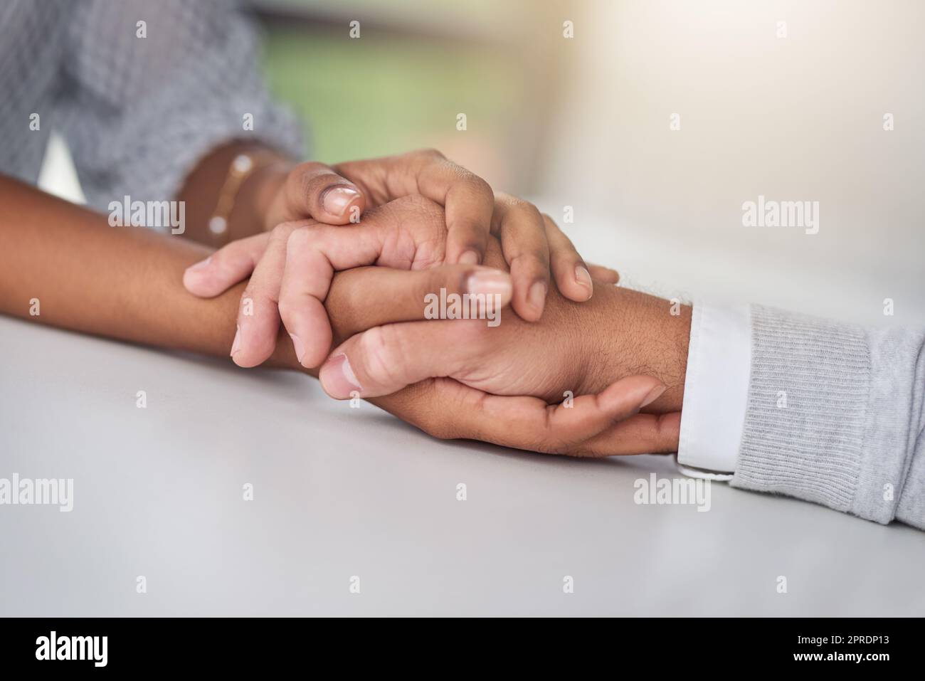 The company that promotes a culture of kindness. a businessman and businesswoman compassionately holding hands at a table. Stock Photo