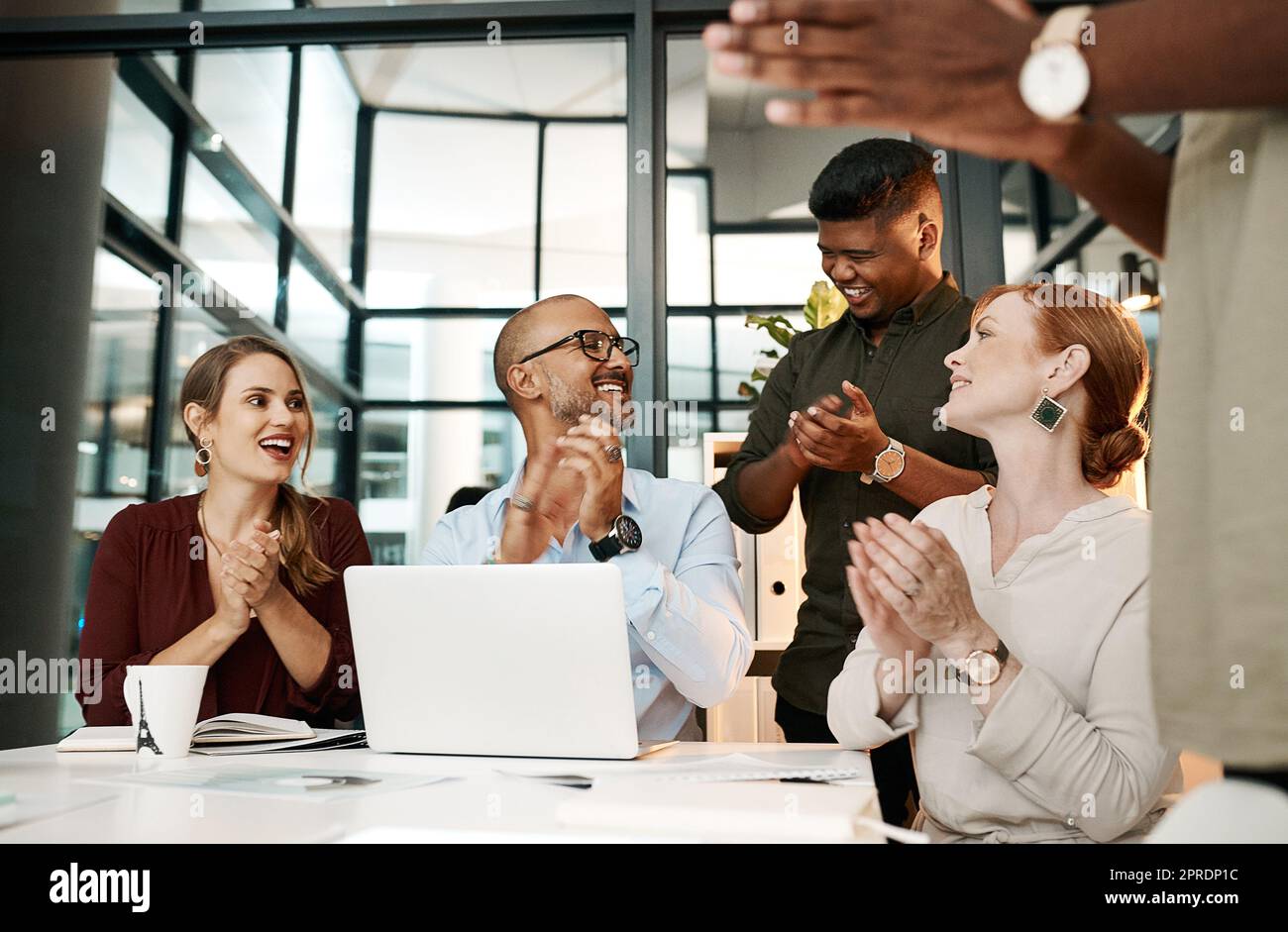 Excited business people clapping in meeting, celebrating success and cheering for good teamwork while working on a laptop together at work. Colleagues having fun after victory and showing support Stock Photo