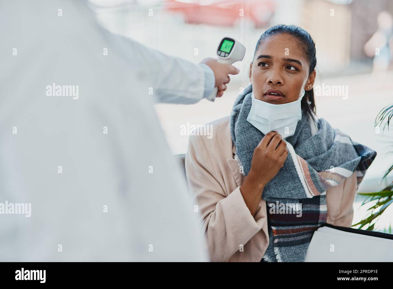 Covid temperature scanning a woman head at the border or an airport with real scared, concerned and serious expression on her face. Traveling refugee or foreign lady with a face mask in quarantine Stock Photo