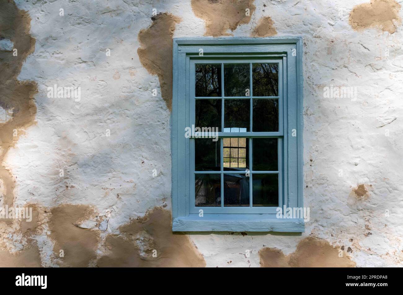 Antique twelve pane window in colonial stone cottage with repairs Stock Photo