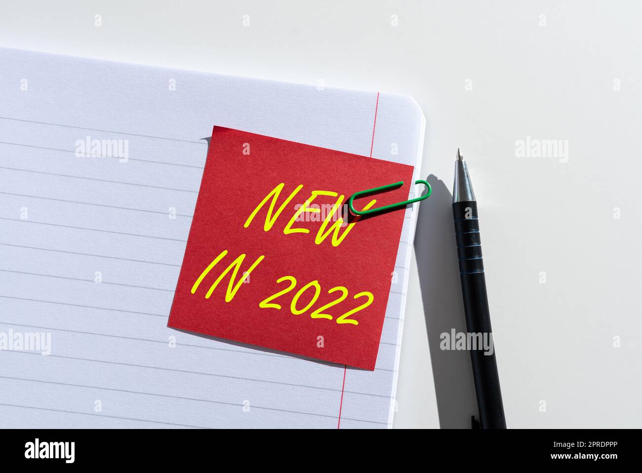 Text sign showing New In 2022. Conceptual photo list of fresh things got introduced this year or the next Sticky Note With Important Idea Clipped On Opened Notebook On Desk With Pen Stock Photo