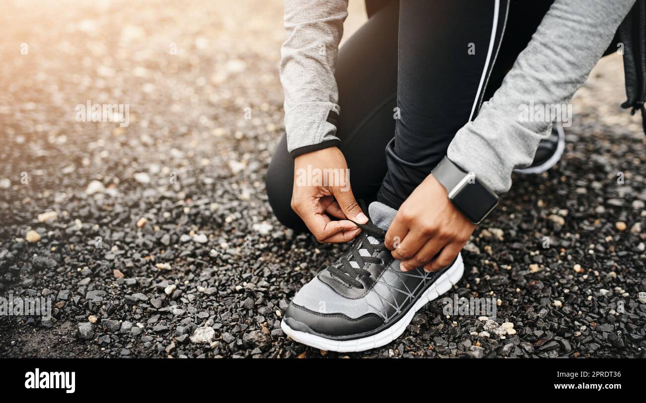 Comfort is the most important feature of a running shoe. Closeup shot of a sporty woman tying her shoelaces while exercising outdoors. Stock Photo