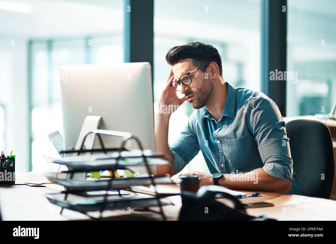 Stress, anxiety and worry with a business man feeling frustrated, irritated and annoyed with work and deadlines. Unhappy and negative male employee suffering from a headache or migraine in his office Stock Photo