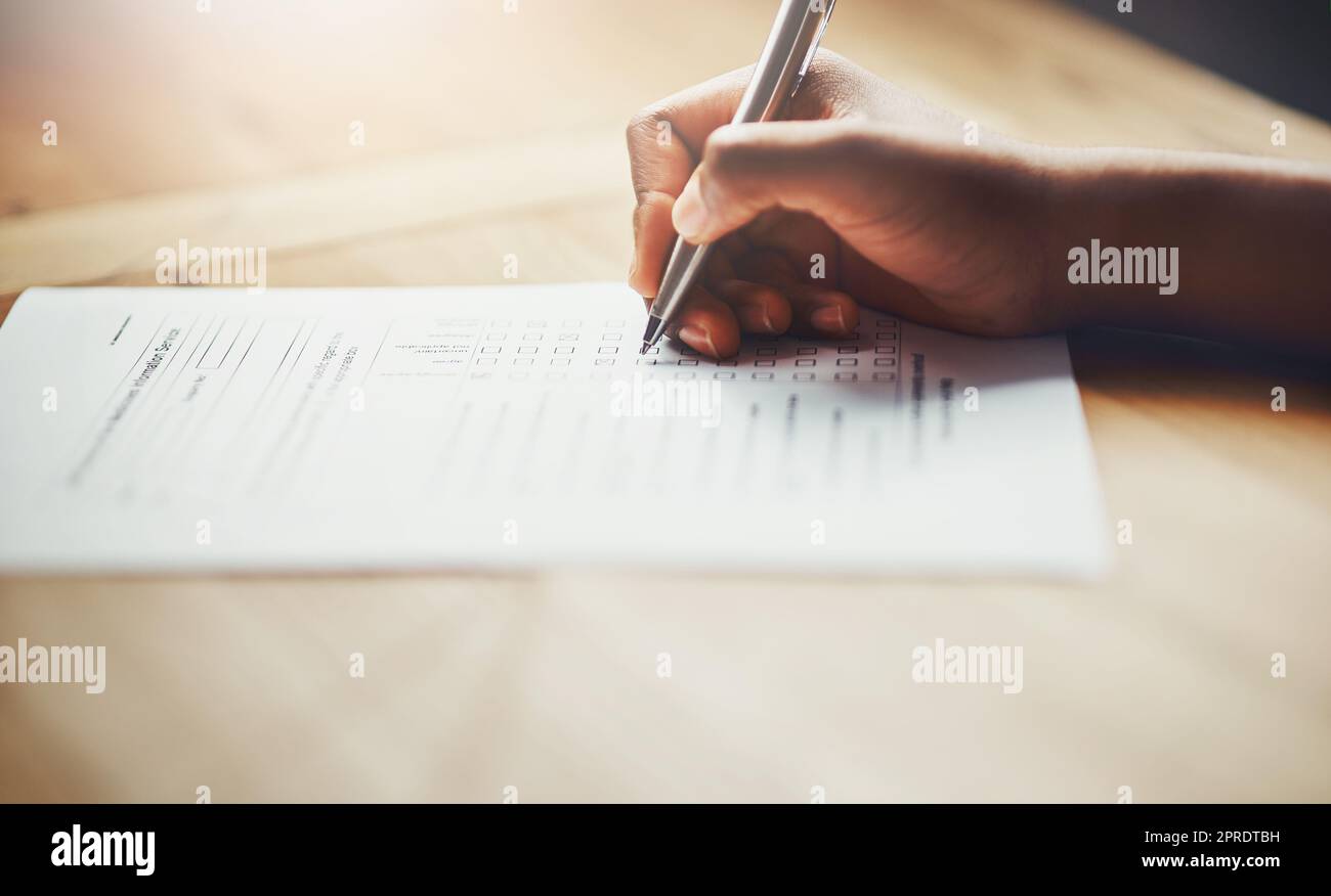 Closeup of business hands of a person filling out paperwork. Hand of an individual writing test, information or survey on paper to complete application or contract form on the desk at work. Stock Photo