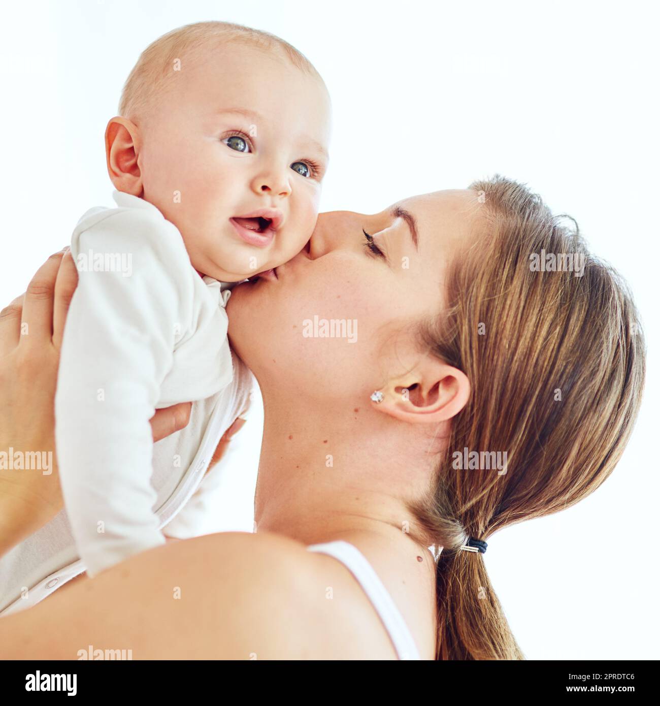 Loving, caring and affectionate mother kissing and bonding with her baby. Female embracing motherhood holding her baby in the air enjoying a sweet moment of love, care and happiness Stock Photo