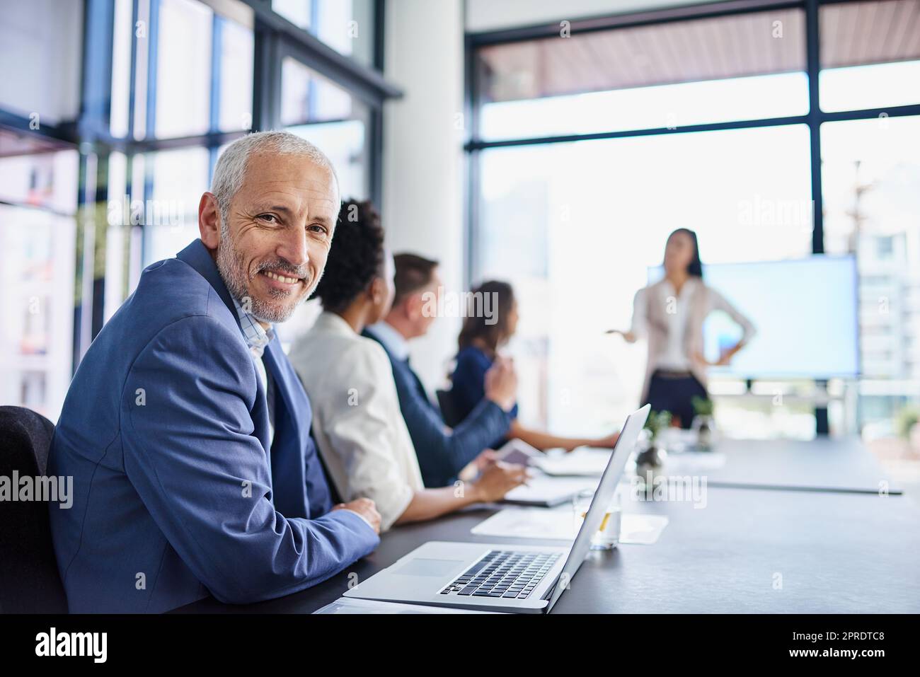 Happy CEO, boss or chairman looking confident in a team meeting at work. Portrait of a proud employee with colleagues as they discuss new innovative plans and strategy in a corporate office Stock Photo