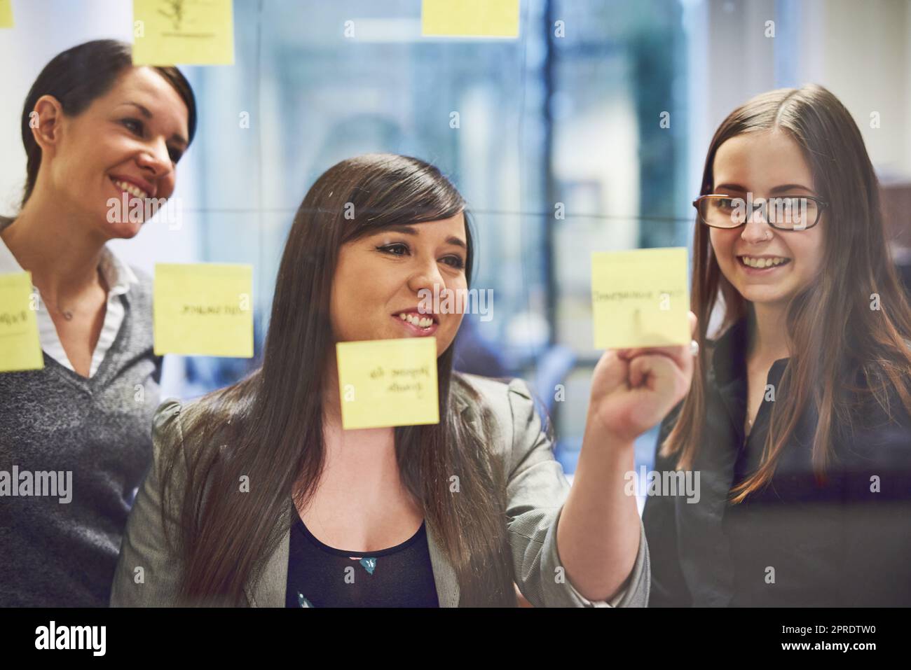 Great ideas makes them happy. a group of businesswomen brainstorming on a glass wall in an office. Stock Photo