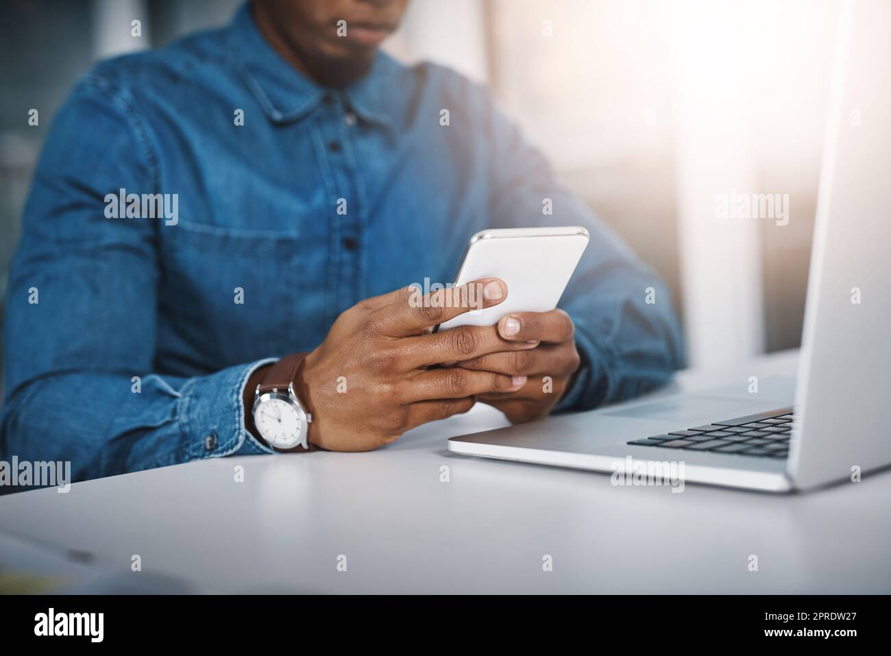 Handling business from multiple digital channels. Closeup shot of an unrecognizable businessman using a cellphone and laptop in an office. Stock Photo