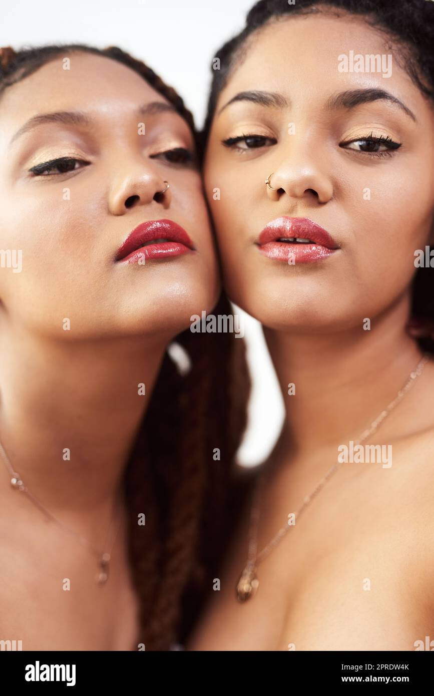 Make up done to perfection. Studio shot of two beautiful young women posing against a grey background. Stock Photo