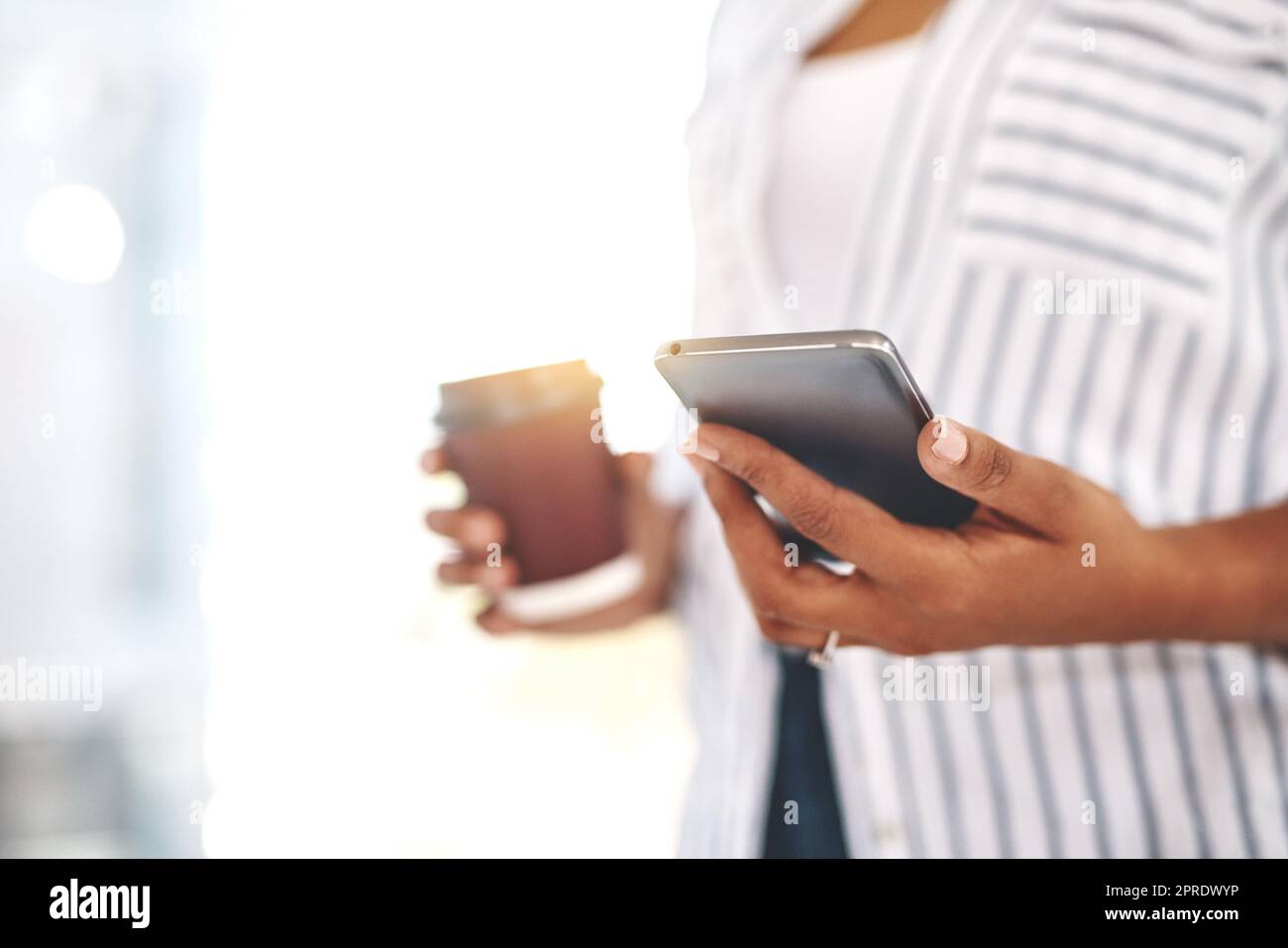 Closeup of professional business woman on her phone working and replying to messages, emails or social media with flare. Black female businessperson holding work and personal cellphone in her office Stock Photo