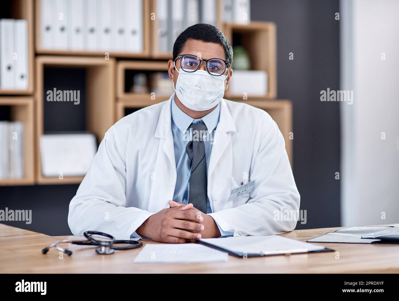Doctor wearing covid mask in clinic to prevent spread of pandemic virus, disease or illness in hospital consult. Portrait of medical professional, healthcare oe frontline worker ready to treat people Stock Photo