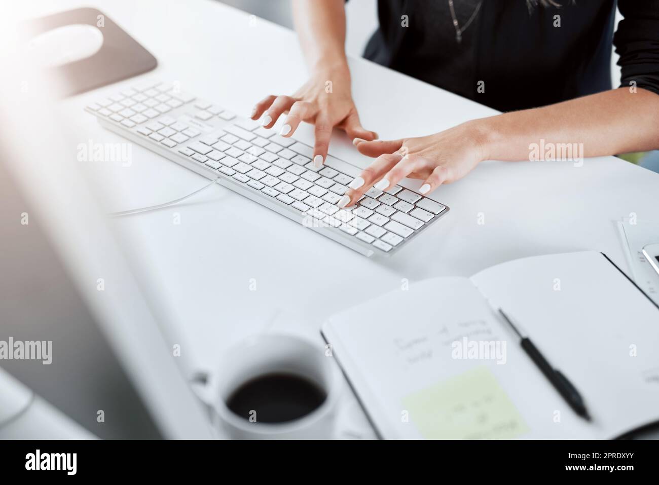 Flying across the keyboard at lightening speed. a businesswoman using a computer at her desk in a modern office. Stock Photo