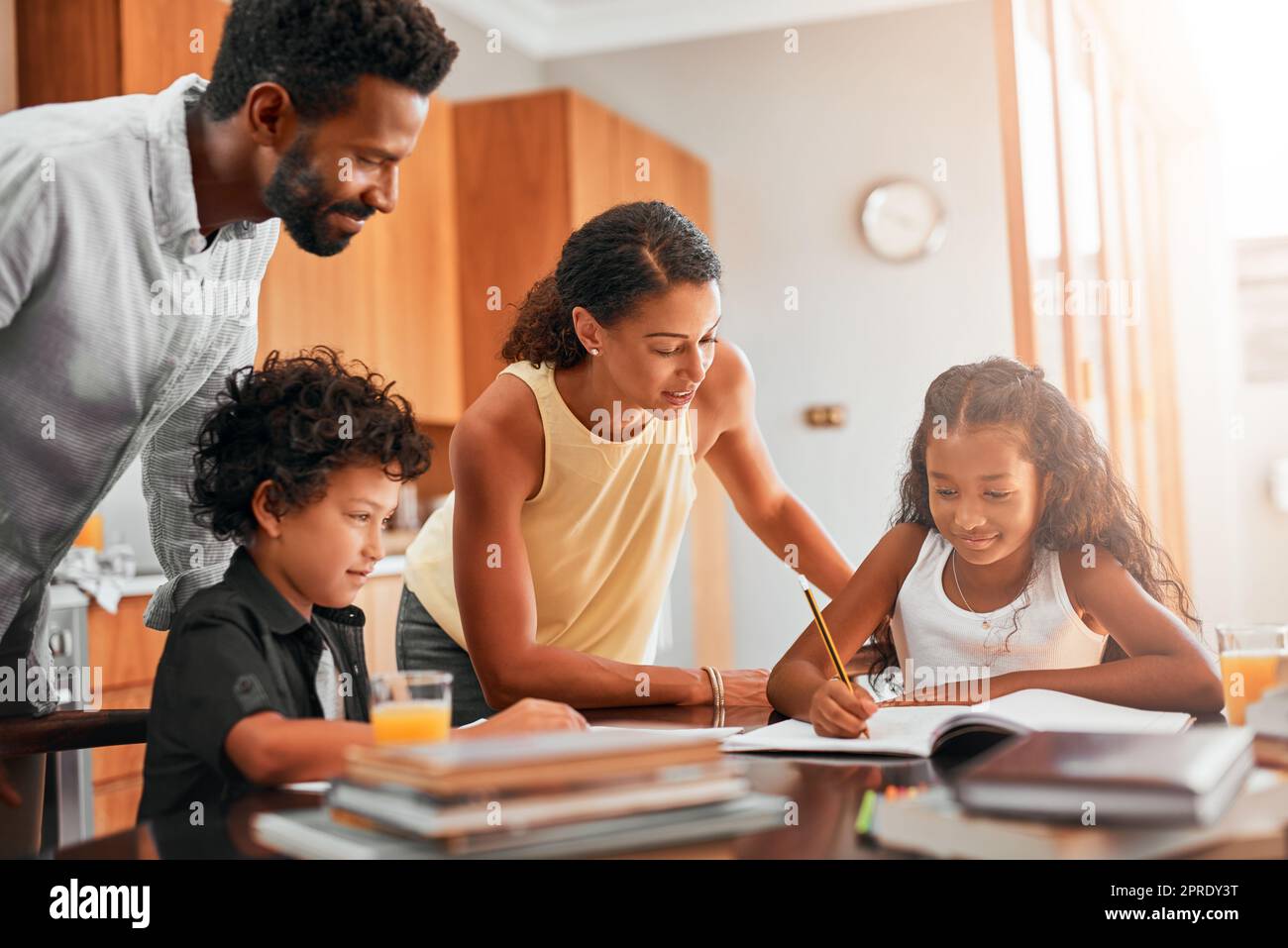 Getting homework done before playtime. parents helping their two children with their homework. Stock Photo