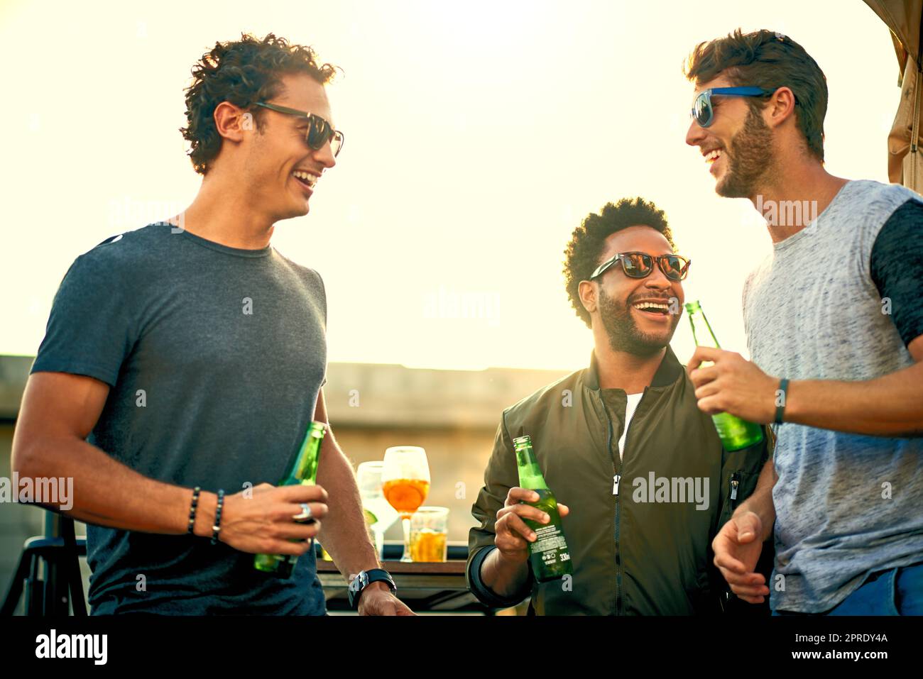 Friends dont let friends have fun alone. a group of young friends hanging out and having drinks together outdoors. Stock Photo
