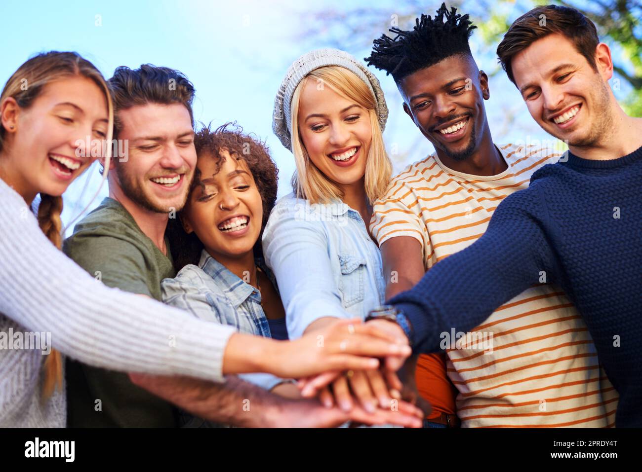 All in this together, all in it for the year. a group of diverse students huddled together with their hands piled on top of each other. Stock Photo