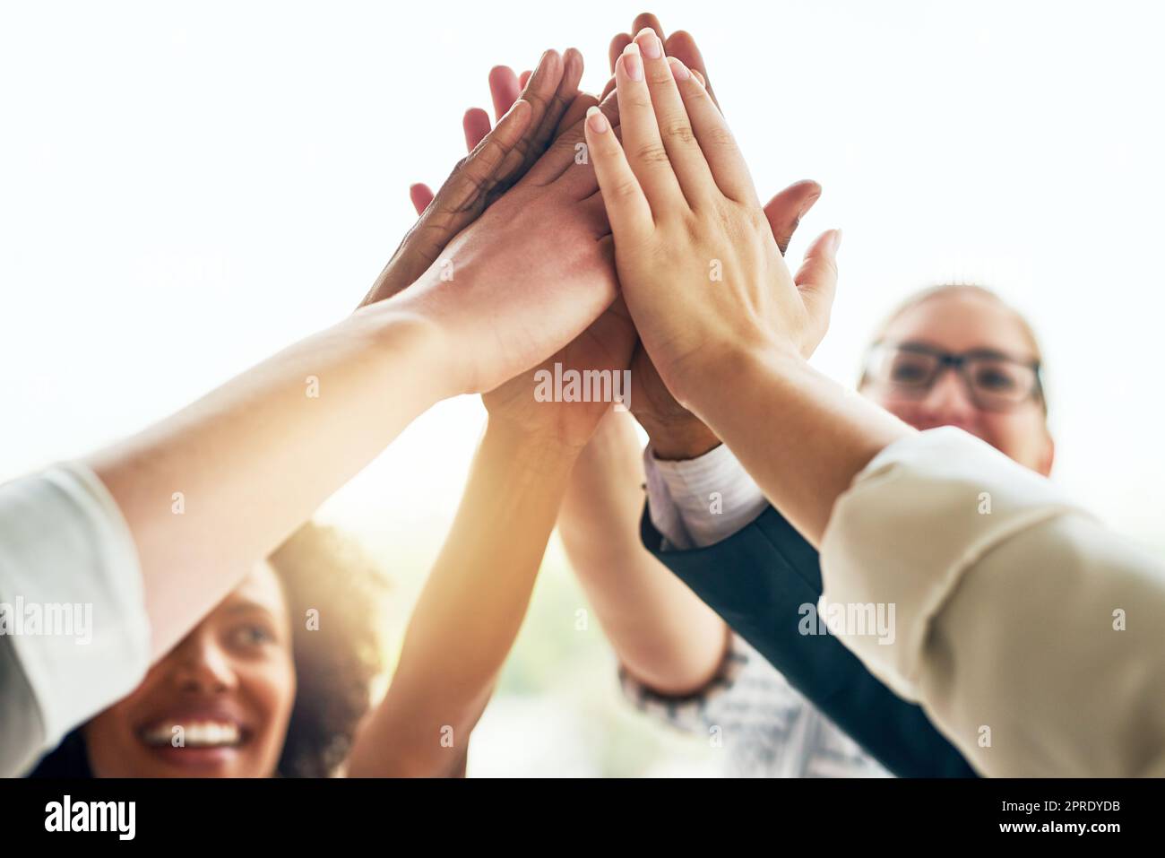 Doing great things together. a group of unrecognizable businesspeople high fiving while standing in their office. Stock Photo