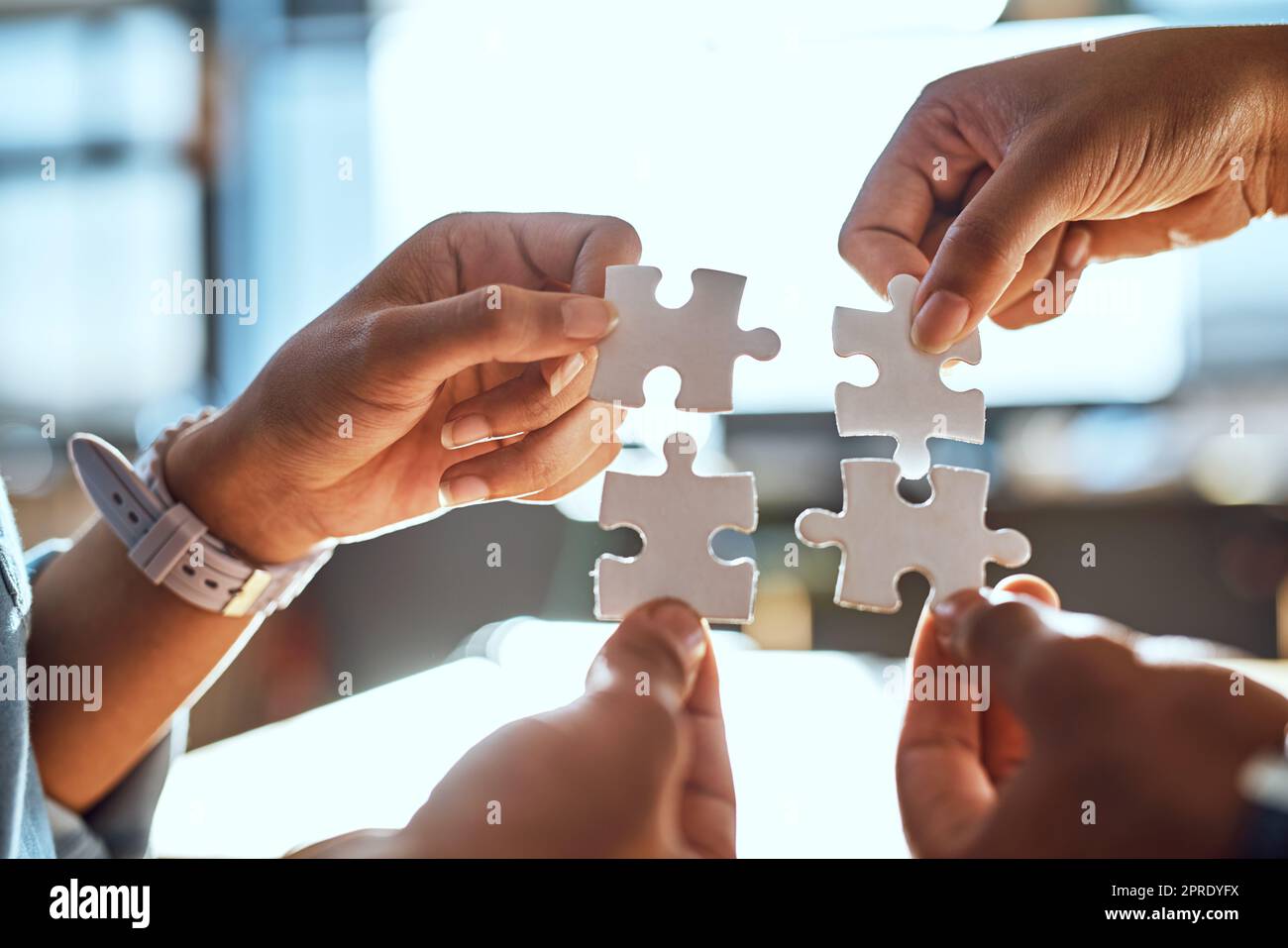 We all form a piece of the bigger picture. Closeup shot of an unrecognizable group of people joining puzzle pieces together. Stock Photo