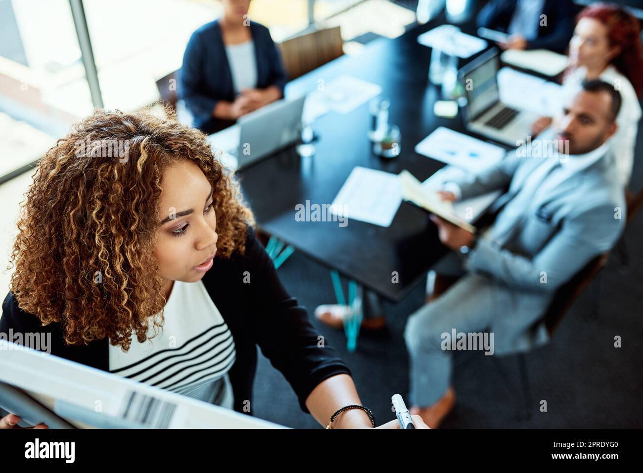 Helping her team see the bigger picture. a businesswoman giving a presentation to her colleagues on a whiteboard. Stock Photo