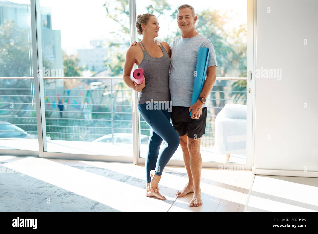 Shes my inspiration. Full length shot of an affectionate mature couple standing with their yoga mats at home. Stock Photo