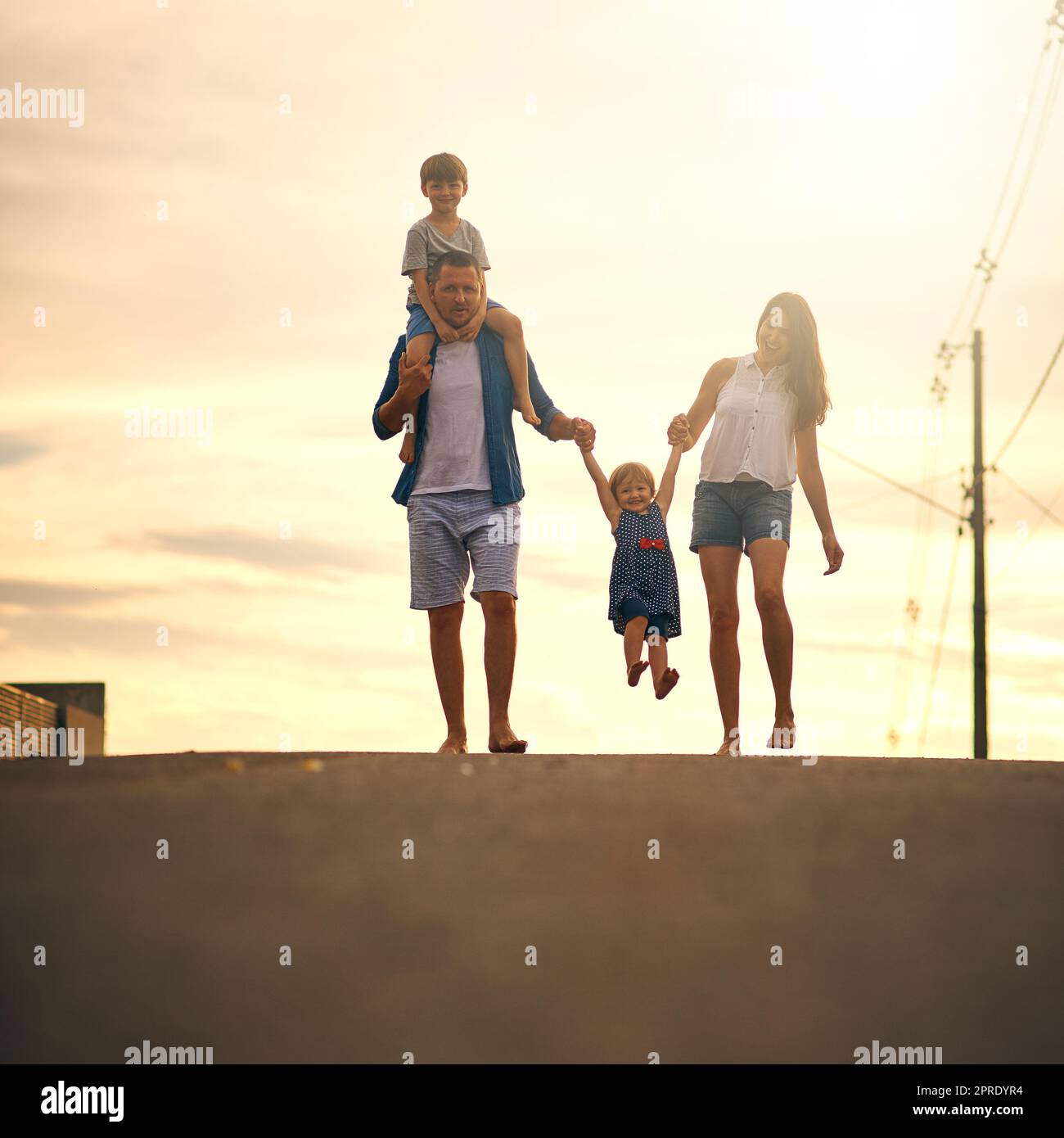 Walking through the neighbourhood as a family. a young family taking a walk down the road outside. Stock Photo