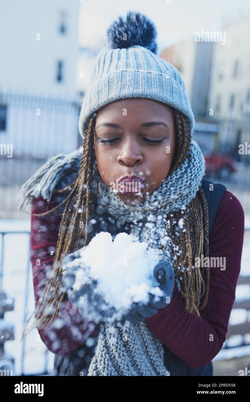 Snow adds that extra sparkle to life. a beautiful young woman blowing a snowball on a wintery day outdoors. Stock Photo