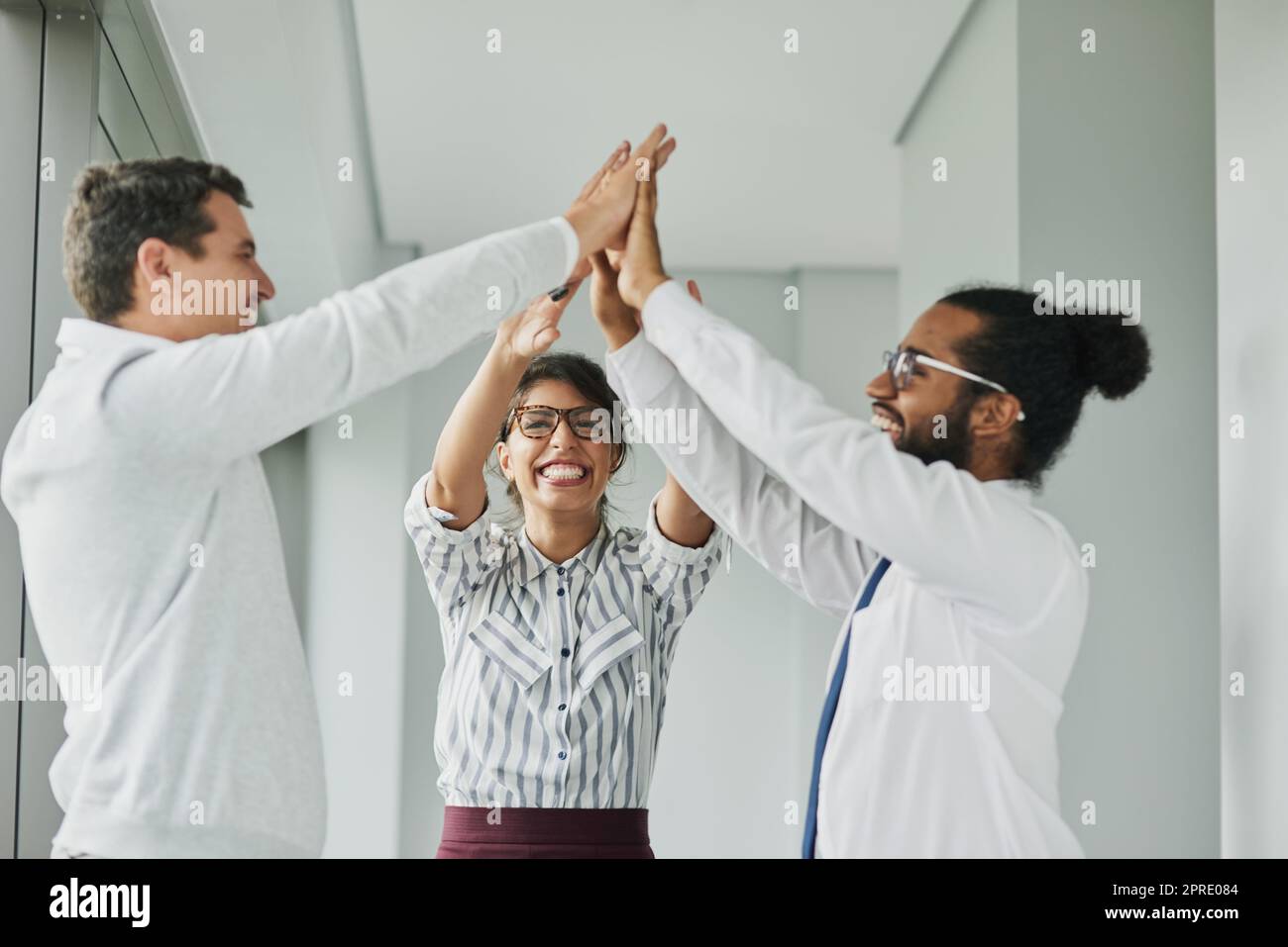 Uniting together in the name of success. a group of businesspeople high fiving together in an office. Stock Photo
