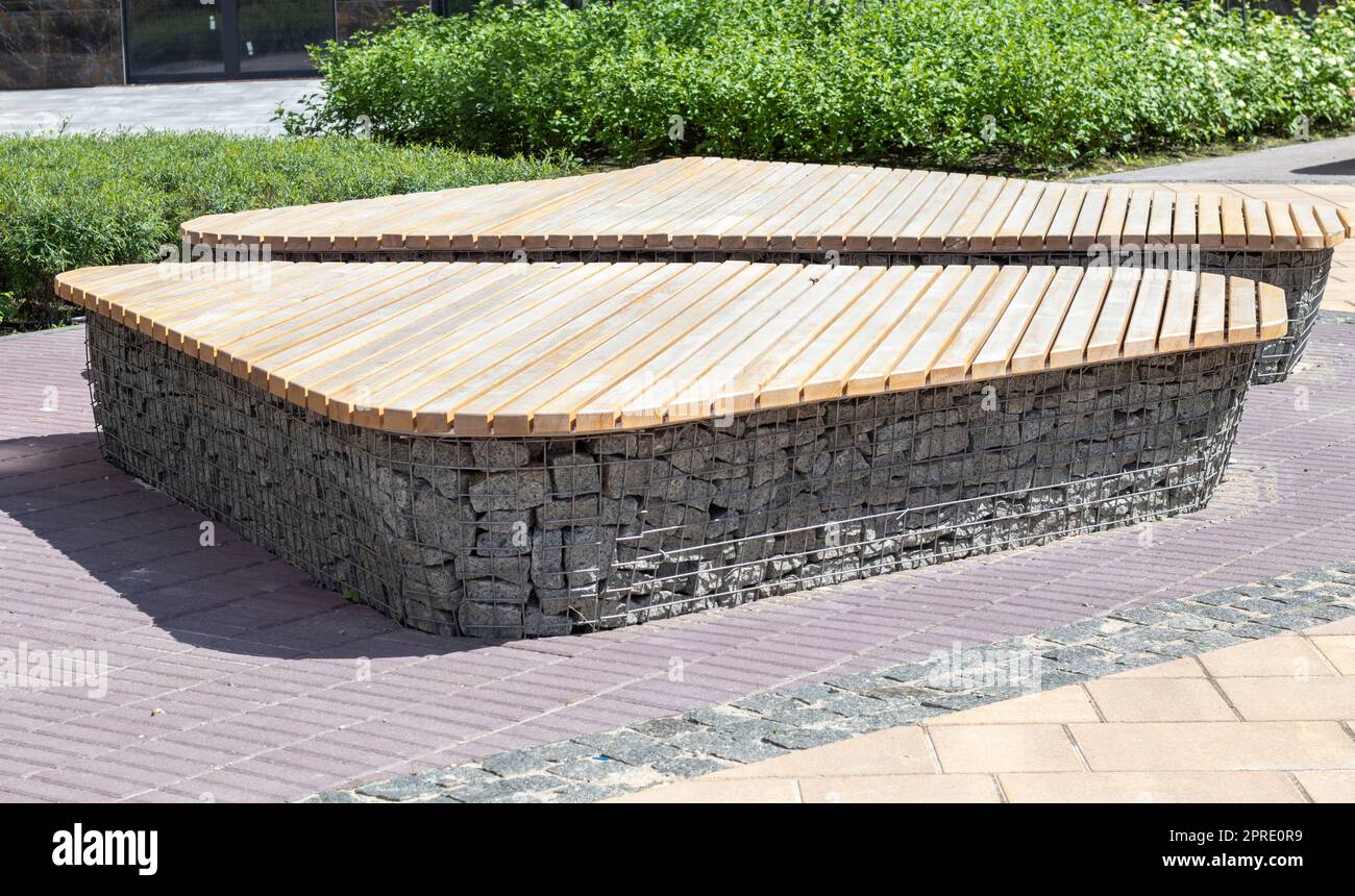 Wooden benches from gabion baskets with stones inside. Wood mounted on gabions. Benches of
