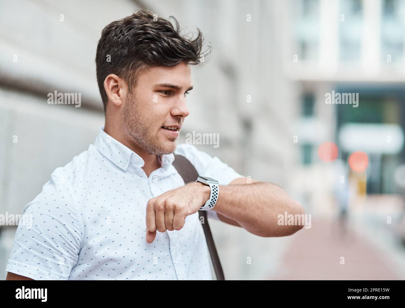 Chatting on a smartwatch with a young creative business man or intern commuting in the city. Hailing a cab, taxi or ride with an app on wireless technology. Male employee travelling to and from work Stock Photo