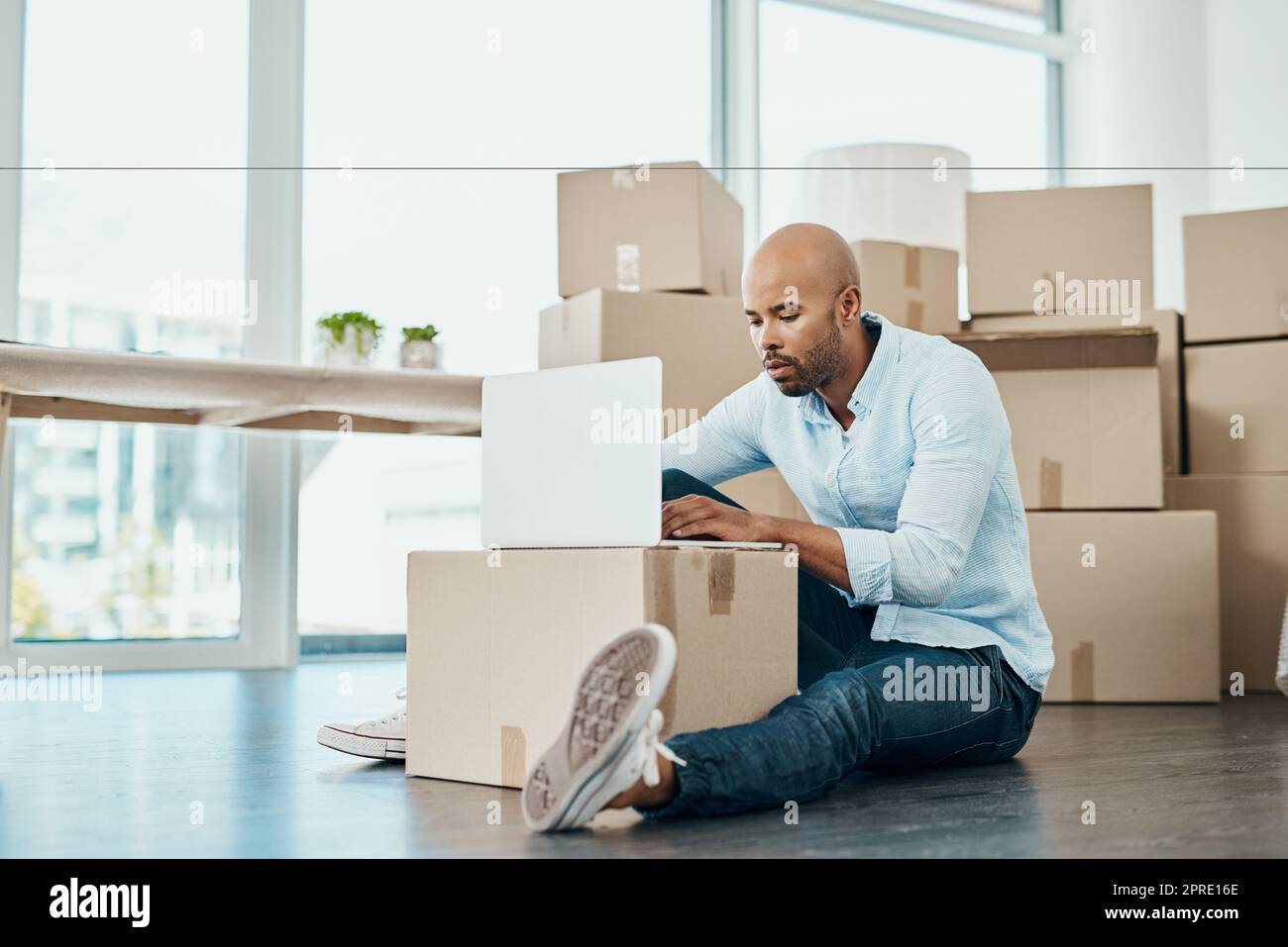 Browsing for ideas to upgrade his living space. a young man using a laptop while moving house. Stock Photo
