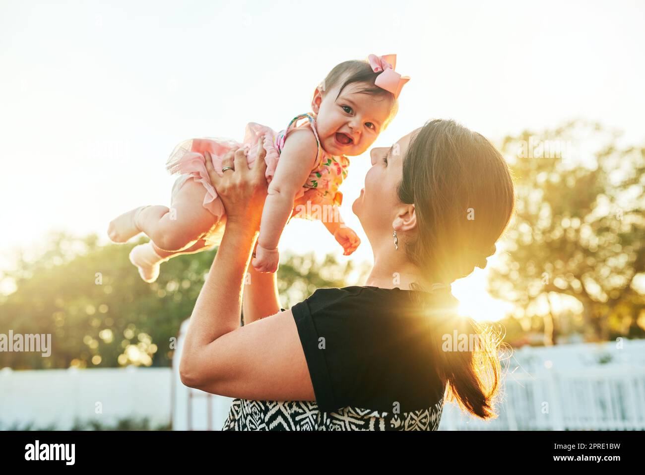 How I wouldnt mind you staying tiny forever. a mother kissing her adorable baby on the cheek in the backyard at home. Stock Photo