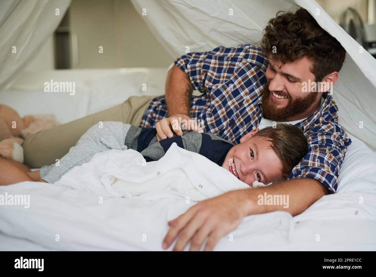 My favourite place to rest. Cropped portrait of an adorable little boy lying on the bed at home with his dad. Stock Photo