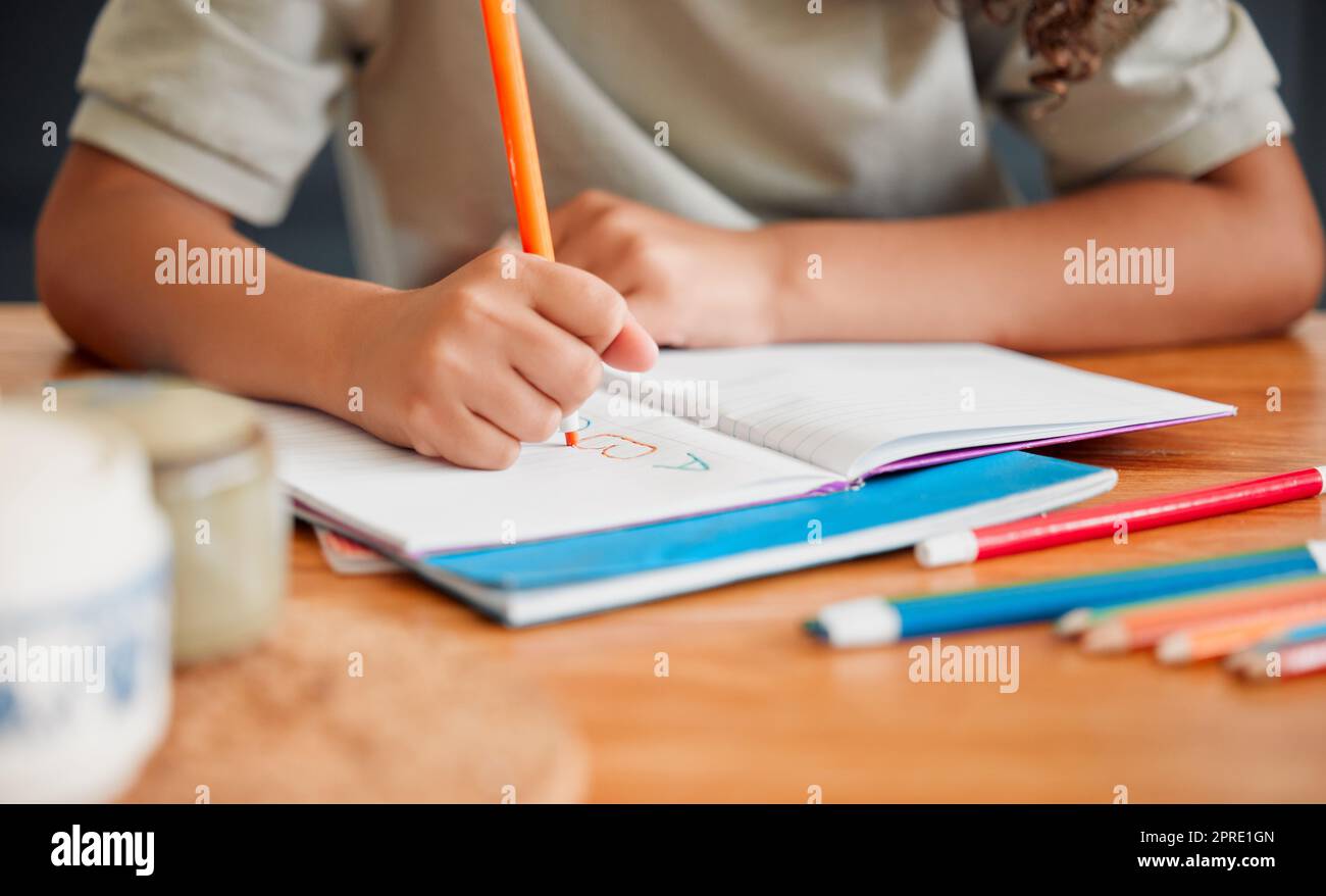 Child coloring, drawing and doing art activity in book in home living room while having fun, enjoying and feeling playful. Closeup hands of small, little and young creative girl expressing with color Stock Photo
