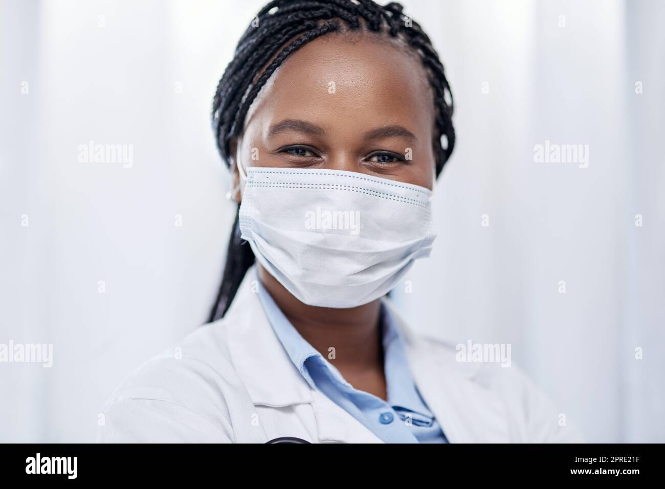 Doctor wearing hygiene face mask for covid, safety and precaution in the healthcare industry. Portrait and face of confident black medical practitioner and coronavirus frontline worker in a hospital Stock Photo