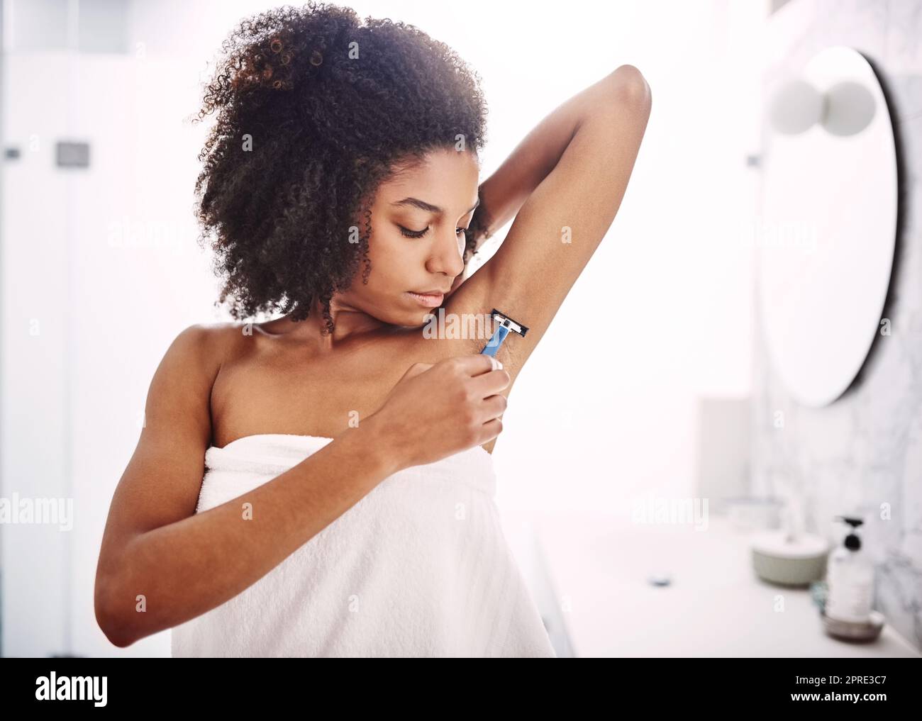 Body care is every womans beauty secret. an attractive young woman shaving her under arms with a razor in the bathroom. Stock Photo