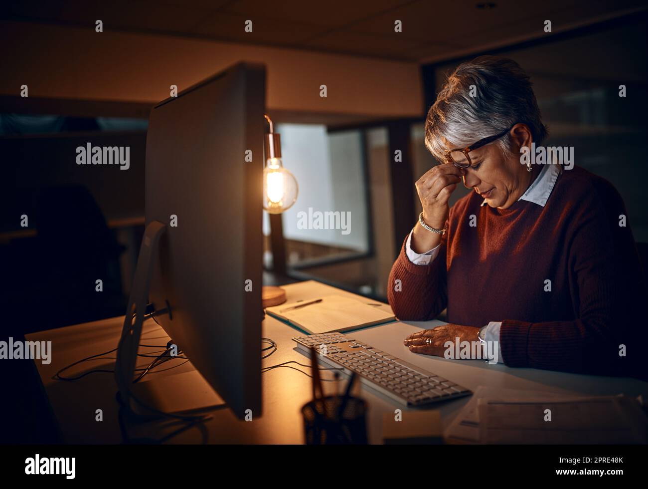 When the pressures of work become too unbearable. a mature businesswoman looking stressed out while working late in an office. Stock Photo