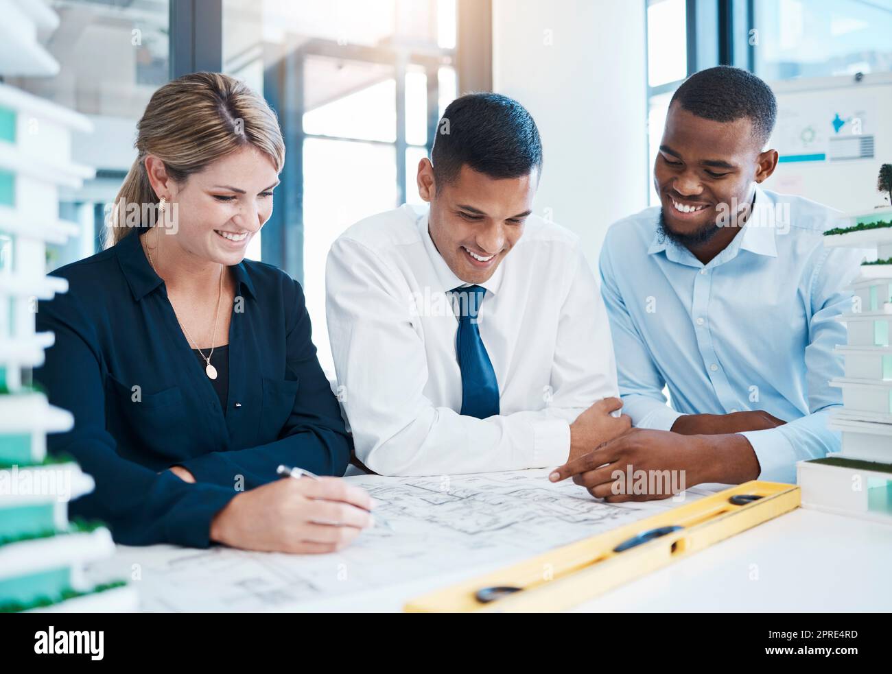 Architect, builder and engineer working together as a construction team on plans and blueprints in their architectural office. Architecture and design with a group of business people discussing work Stock Photo