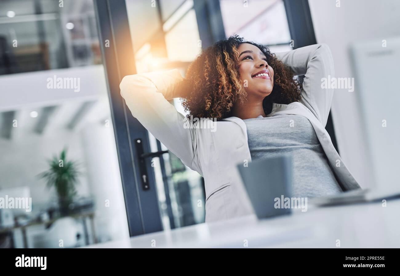 Soaking in the gratifying feeling of accomplishment. a young businesswoman taking a break at her office desk. Stock Photo