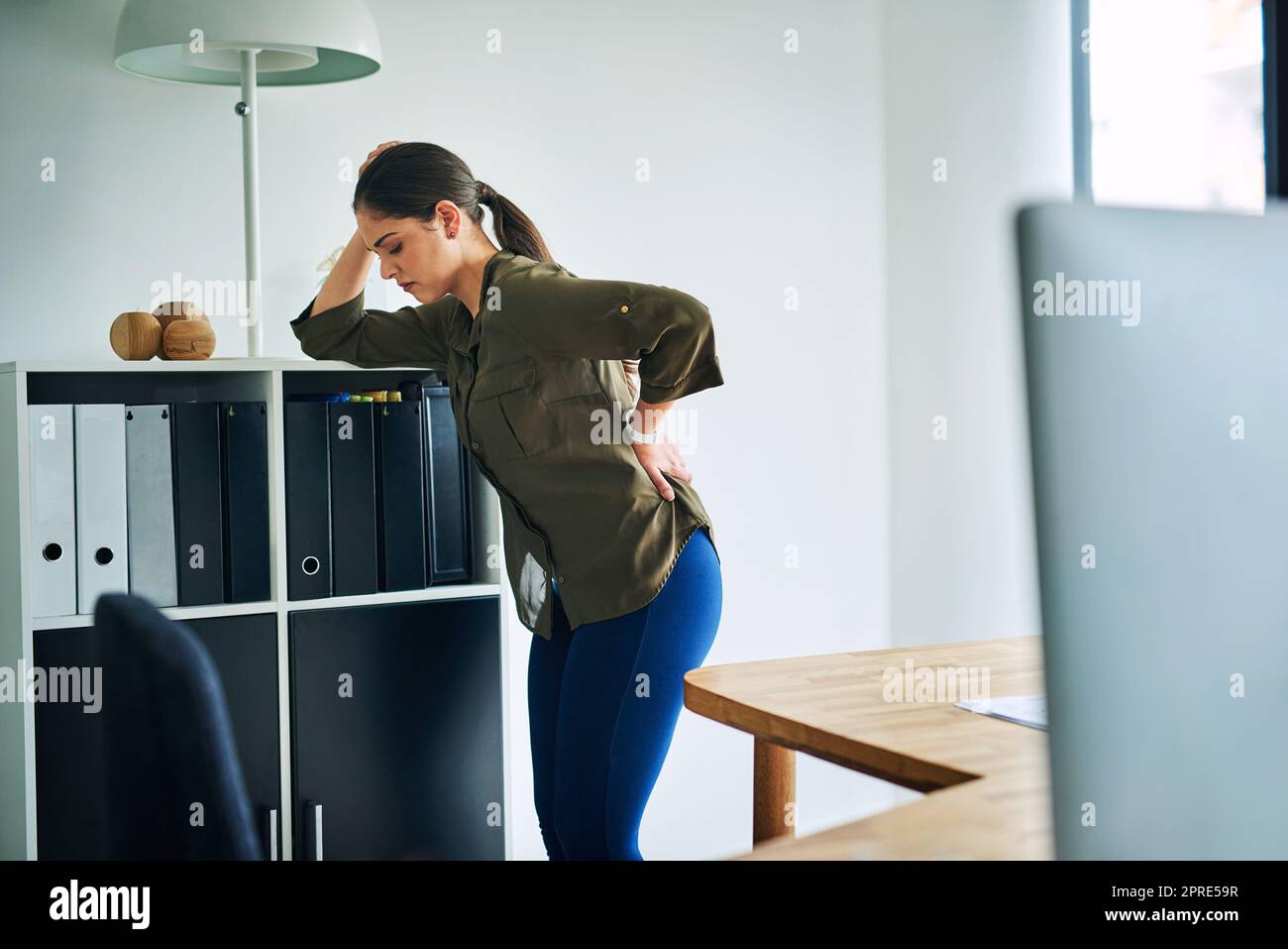 Her back is bearing the brunt of stress. a young businesswoman suffering with back pain in an