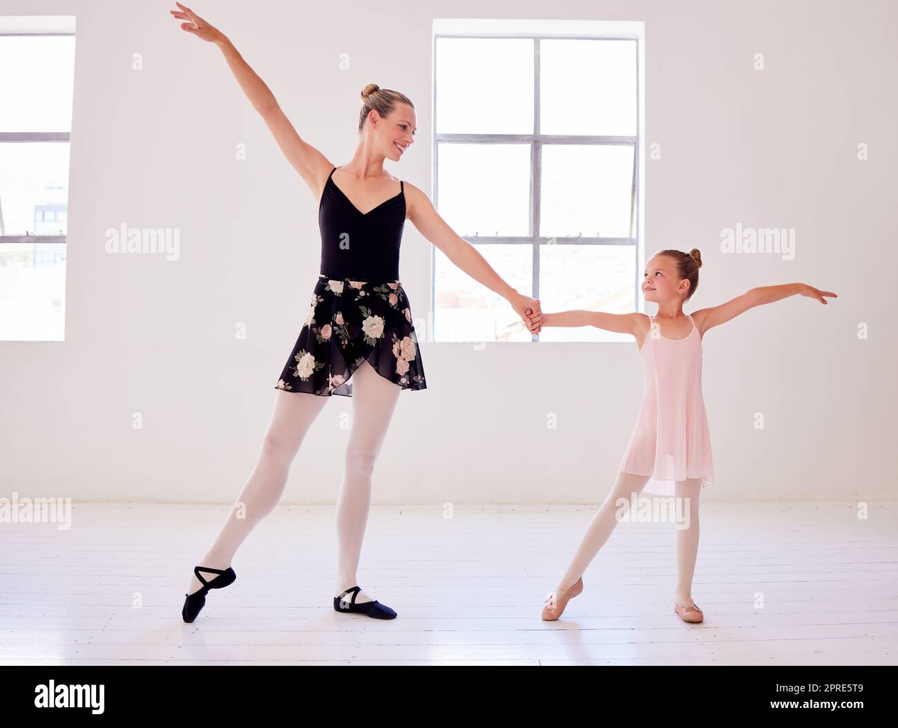 Ballerina, ballet and dance teacher with a child teaching beautiful, elegant and classical choreography in studio. Woman, professional and artist showing little girl graceful routine in pointe shoes Stock Photo
