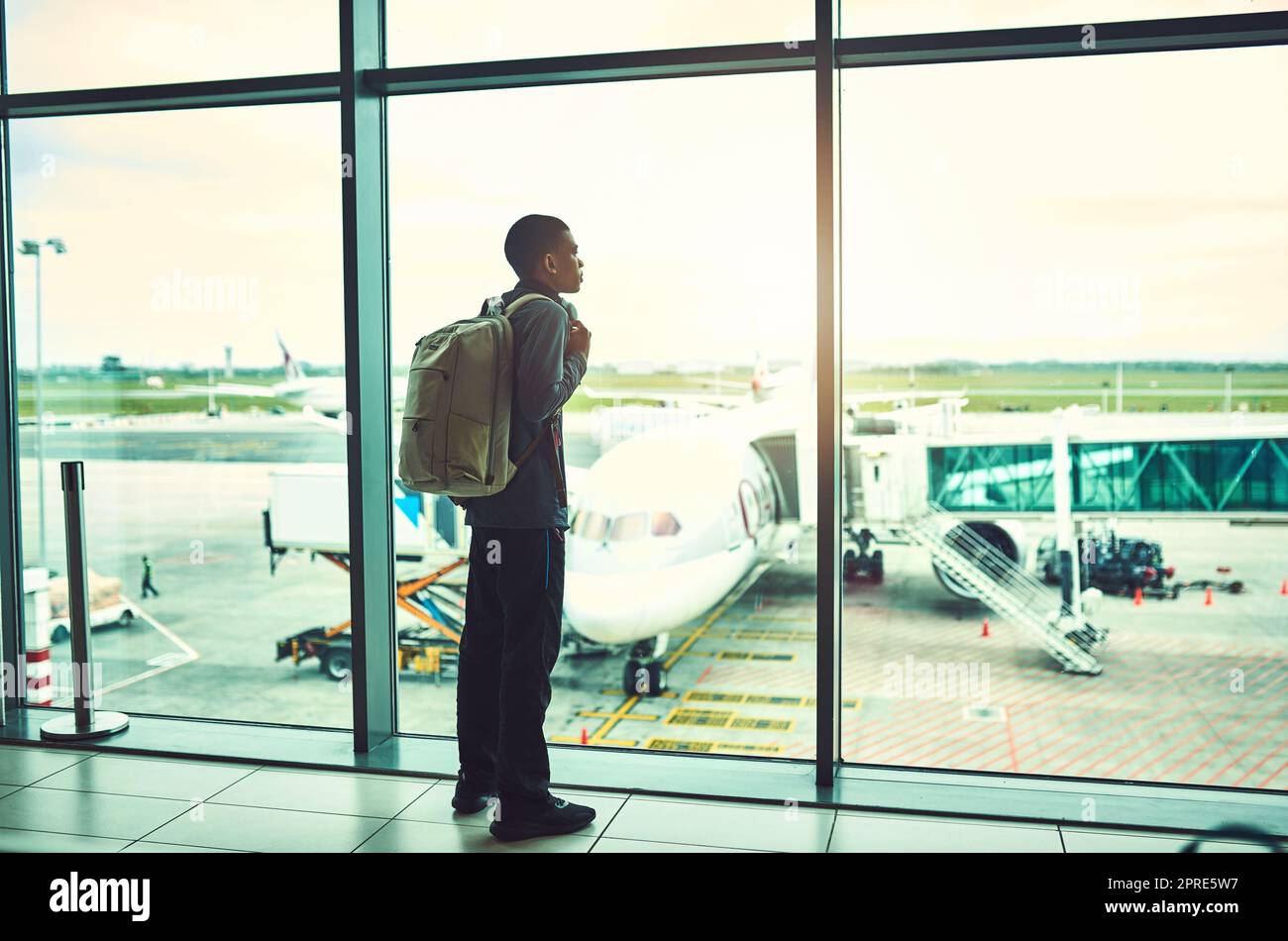Waiting till we take flight. a man looking through the window at an airport. Stock Photo