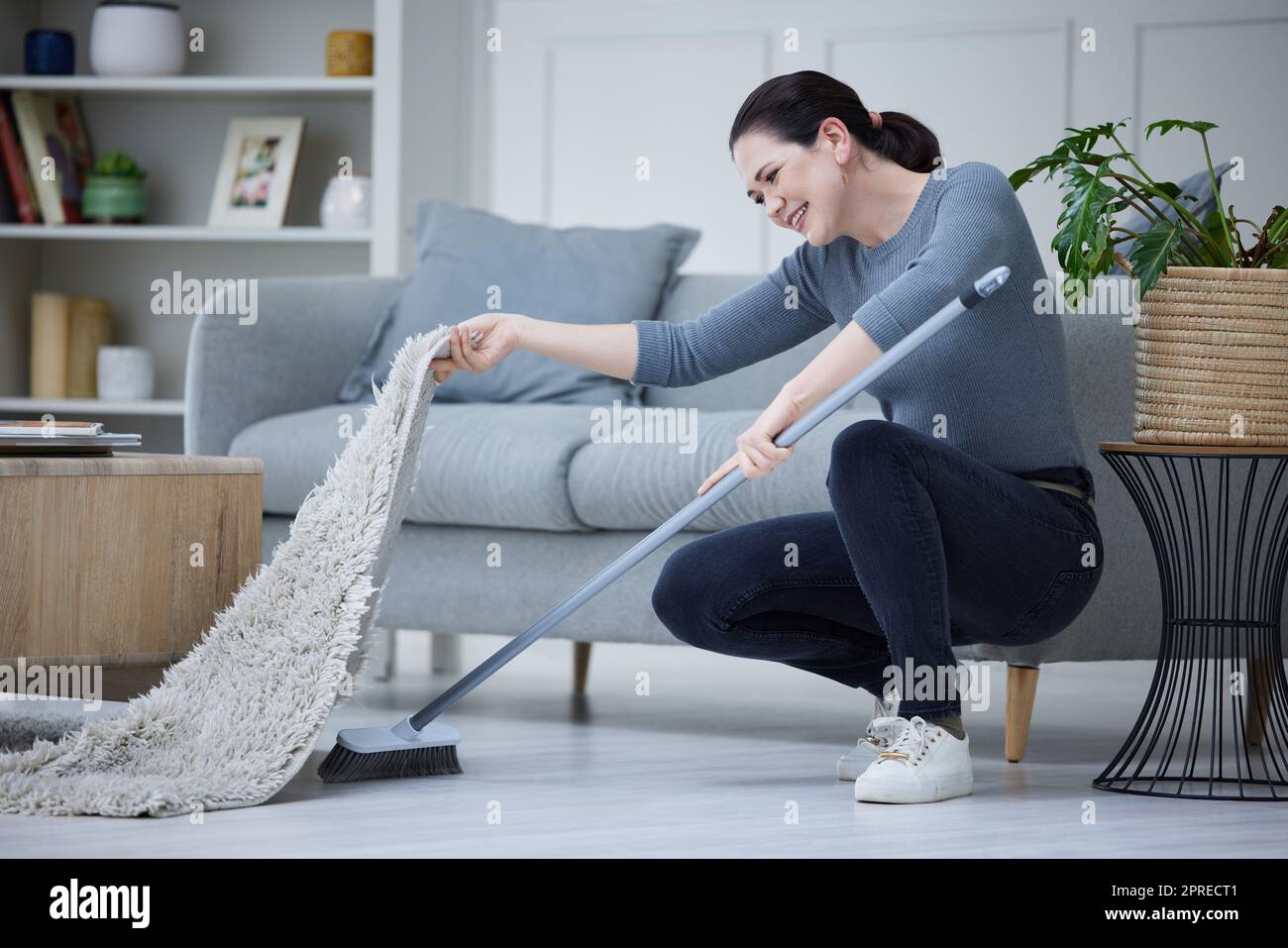 Woman, cleaning home and with broom sweeping carpet for daily chores