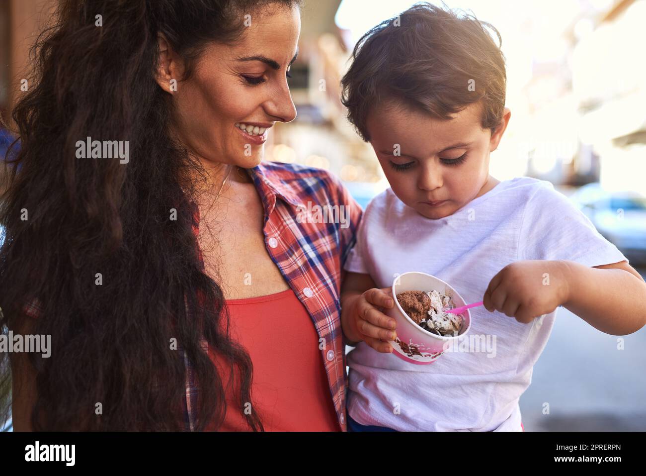 Tell me how it tastes. an attractive young woman and her young son at an ice cream shop. Stock Photo