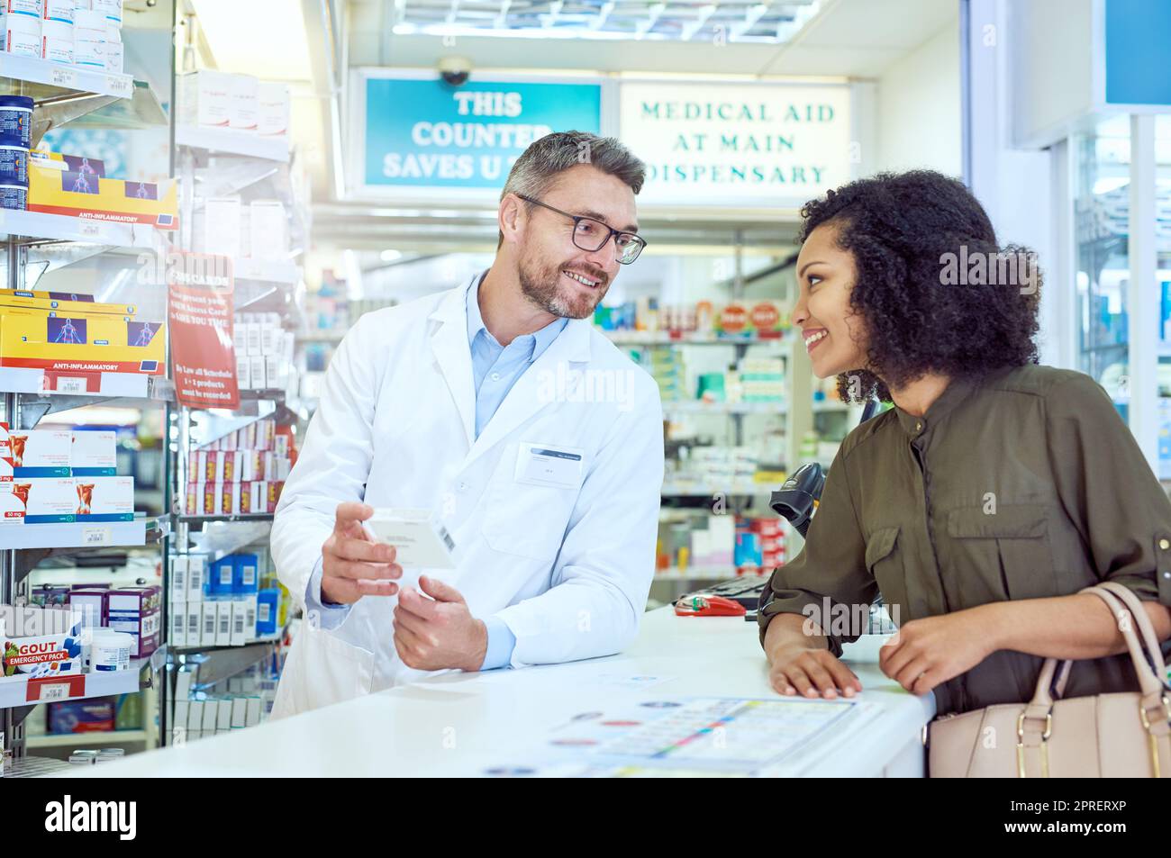 Take two of these after a meal. a handsome mature male pharmacist helping a female customer in the pharmacy. Stock Photo
