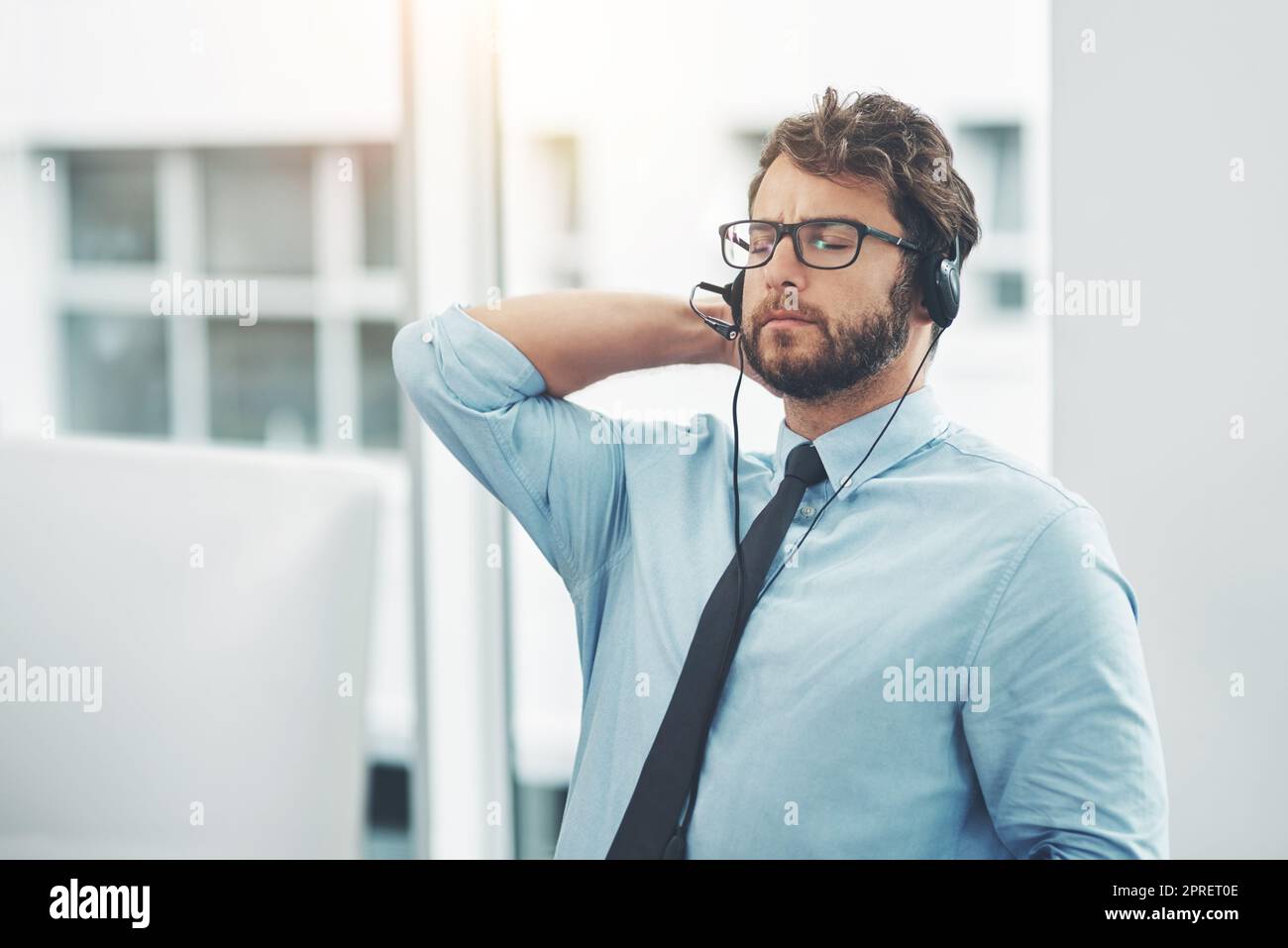 Getting a difficult call 5 minutes before home time. a young man experiencing stress while working in a call center. Stock Photo