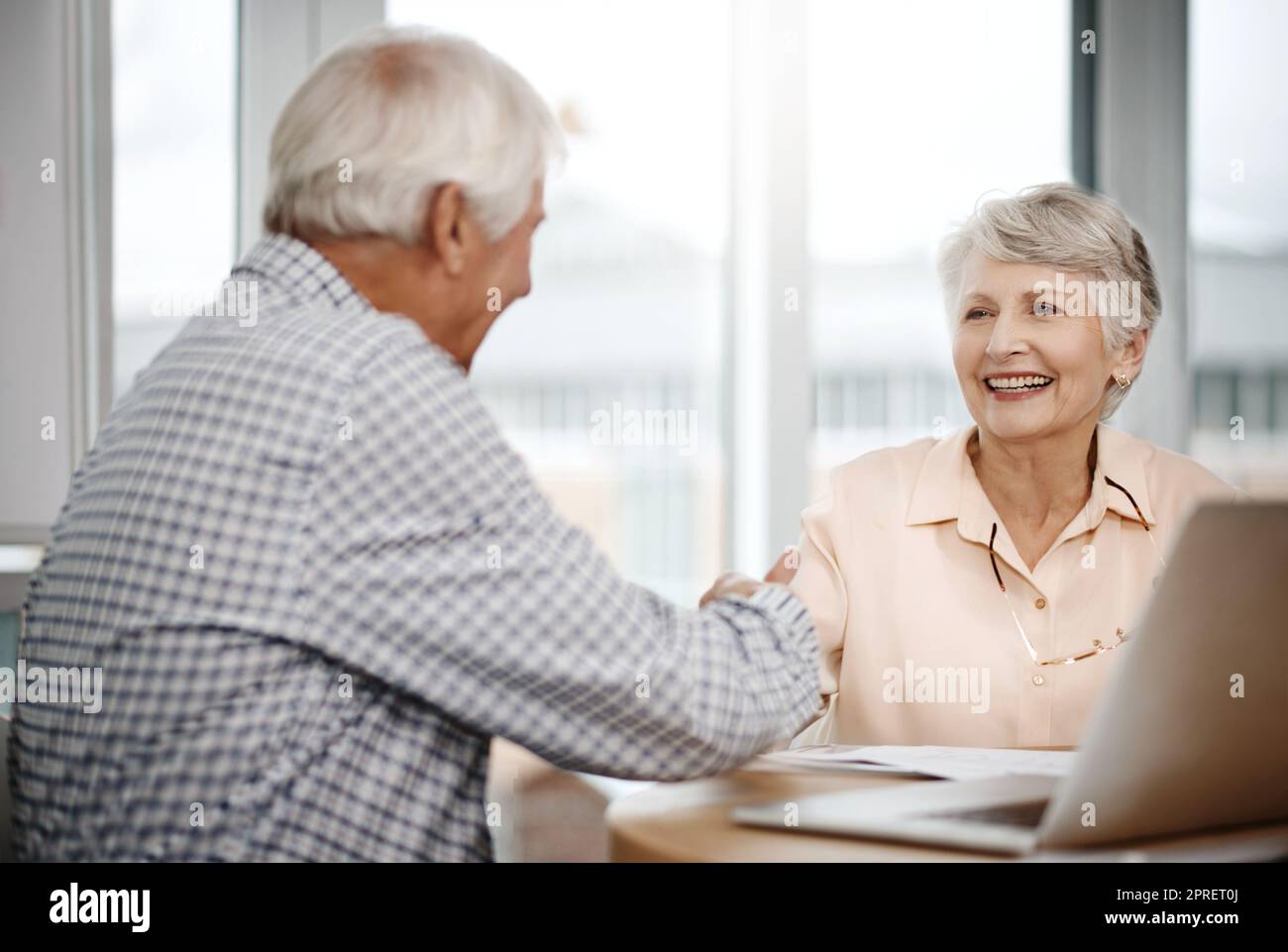 Weve prepared well for this. an affectionate senior couple shaking hands while working on their finances at home. Stock Photo